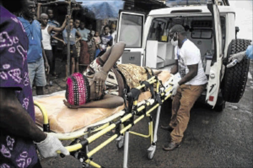 DESPAIR: A pregnant woman suspected of being infected with ebola is helped by inadequately attired workers in Freetown, Sierra Leone photo: reuters