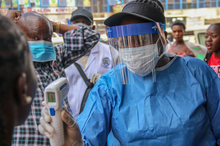 A health worker takes the temparature of locals on Tom Mboya Street on March 22.