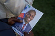 A person holds a photo of late Haitian President Jovenel Moise.