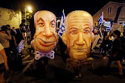 Demonstrators wear masks depicting Israeli Prime Minister Benjamin Netanyahu and Israel's Alternate Prime Minister and Defence Minister Benny Gantz during a protest against Israeli Prime Minister Benjamin Netanyahu's alleged corruption and economic hardship stemming from lockdown during the coronavirus disease (Covid-19) crisis, near his residence in Jerusalem August 8, 2020.  