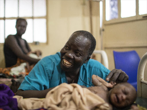 South Sudanese surgeon, Evan Atar Adaha, 52, and winner of the Nansen Refugee Award, with the newborn baby of a refugee from Sudan in the maternity ward of the Maban Hospital in the town of Bunj, Maban County, South Sudan on May 8, 2018. /UNHCR via REUTERS