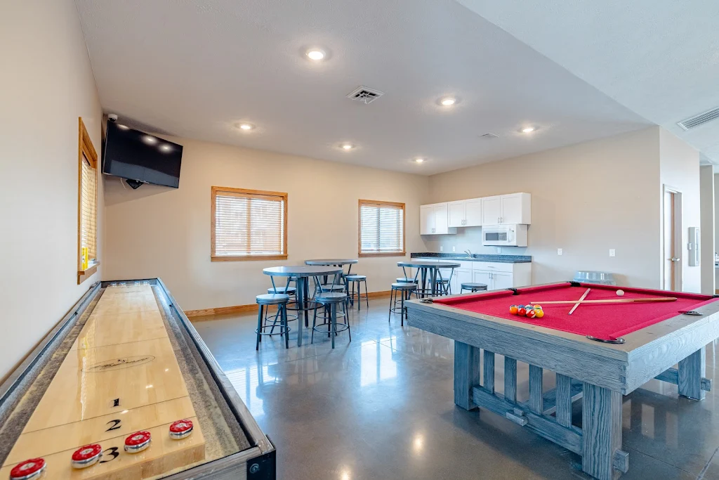 Game room with a shuffleboard, pool table, kitchenette, high-top tables with barstools and a mounted TV