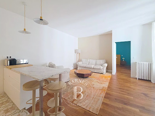 Luxury apartment / penthouse for rent in Paris 6ème (75006) - Neighborhood Saint Placide - Living room with kitchen area and white sofa