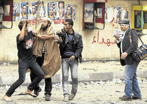 A protester is prevented from throwing stones during clashes with Egyptian security forces near the interior ministry in Cairo on Saturday Picture: SUHAIB SALEM/GALLO IMAGES