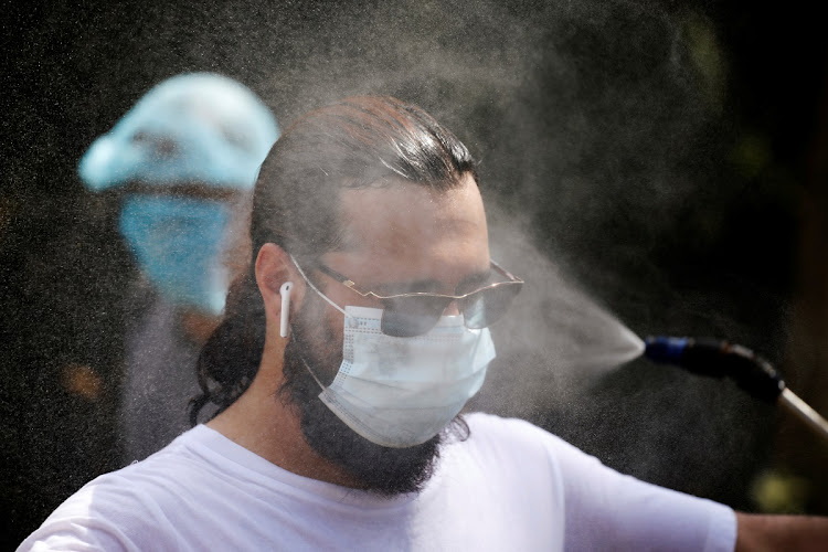 A volunteer from the National Muslim Covid-19 Response Committee, is sprayed with disinfectant after attending a funeral of Abdirizak Hassan Ahmed, at the muslim cemetery in Nairobi, Kenya August 6 2020.