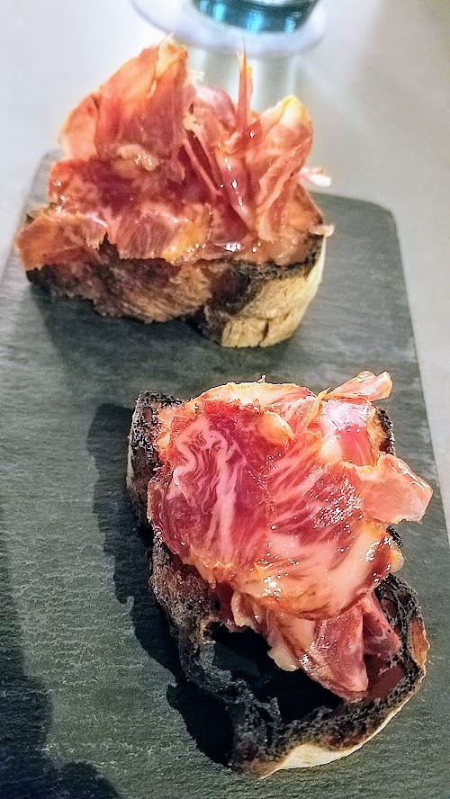 Can Font Happy Hour includes various Montaditos, a tapas of bread mounted with various ingredients. This is the Montadito de Llom with grilled Catalan bread, tomatoes, Iberico cured loin