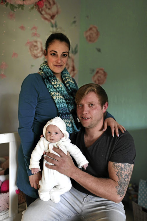 Kyle Wileman and Angelique Wells with their one-month-old daughter Aurora, who tested positive for Covid but survived.