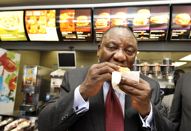 Cyril Ramaphosa tucks into a McDonalds' burger. (File photo.)