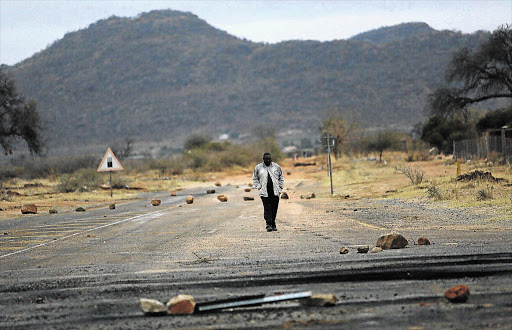 BURNING FUSE: A man walks on a road strewn with rocks leading to Mokopane in Limpopo after a protest by frustrated villagers