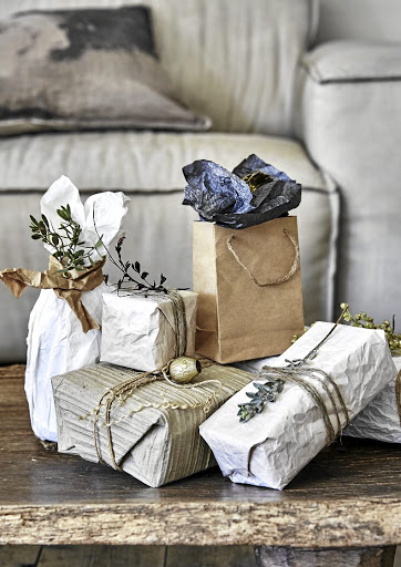 Gifts have been wrapped in brown Kraft paper and plain white newsprint that has been crinkled into tight balls to mimic crushed linen.