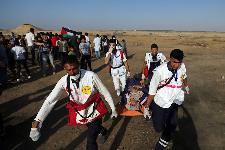 Medics evacuate a Palestinian woman who inhaled tear gas fired by Israeli forces during a protest at the Israel-Gaza border fence, in the southern Gaza Strip, June 21, 2019.