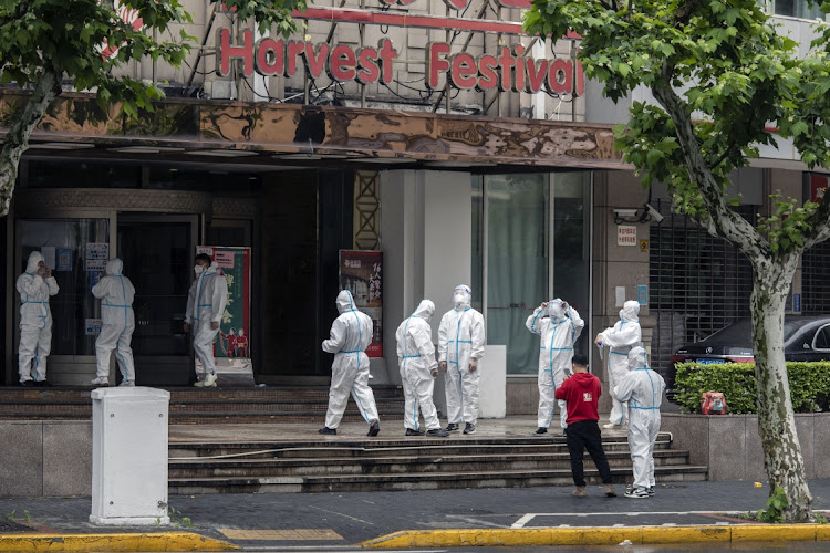 Workers in personal protective equipment prepare to enter a building during a lockdown due to Covid-19 in Shanghai, China, on May 13 2022. Picture: BLOOMBERG