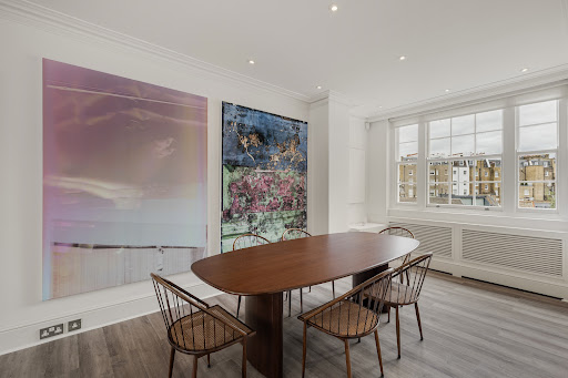 Dining room with oval table and art in this luxury apartment / penthouse for sale in London ($4,660,241)