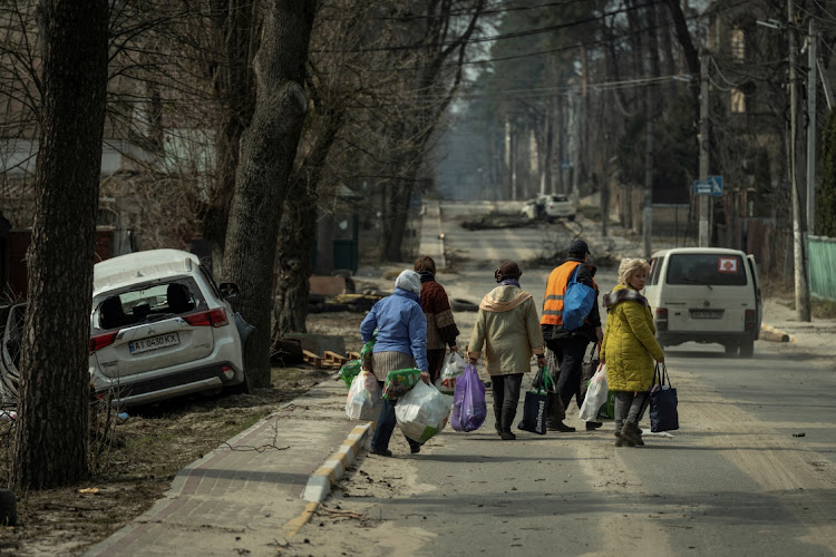 Locals carry food found at a supermarket, as Russia's attack on Ukraine continues, in the town of Irpin, Ukraine, March 29 2022. Picture: SERHI MYKHALCHUK/REUTERS