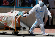 A health worker wearing PPE carries a patient suffering from Covid-19 outside the casualty ward at Guru Teg Bahadur hospital in New Delhi, India. The last 24 hours brought 360,960 new cases for the world's largest single-day total, taking India's tally of infections to nearly 18 million.