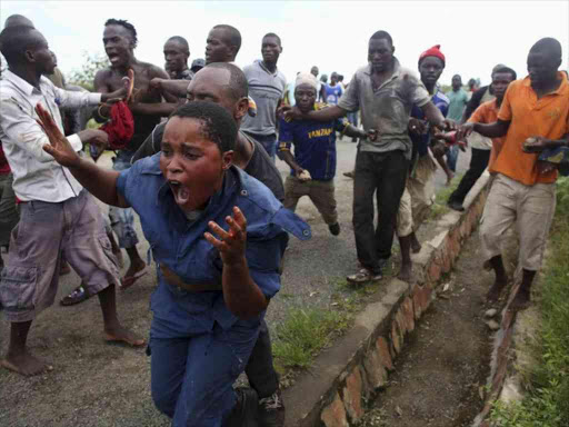 Protesters attack a female police officer accused of shooting a protestor in the Buterere neighbourhood of Bujumbura, Burundi, May 12, 2015. /REUTERS
