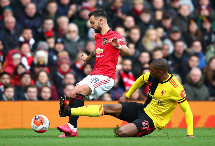 Christian Kabasele of Watford tackles Bruno Fernandes of Manchester United during the Premier League match at Old Trafford on February 23, 2020 in Manchester, United Kingdom.