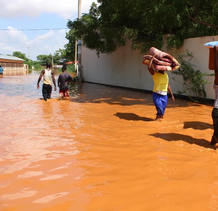 Resident of Buna town wade through floodwaters on Saturday.