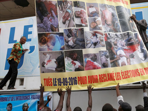 Opposition supporters hold a poster carrying pictures of people killed during last week's protest in front of a opposition party Union for Democracy and Social Progress (UDPS) office in Kinshasa, Democratic Republic of Congo, September 28, 2016. /REUTERS