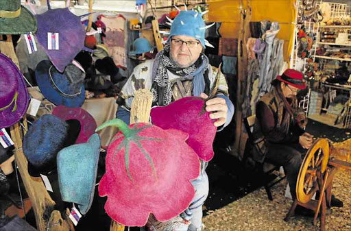 HATS ON: Bathurst milliner Mark Watermeyer spins wool while a festival goer tries to choose the right hat at the National Arts Festival in Grahamstown Picture: DAVID MACGREGOR
