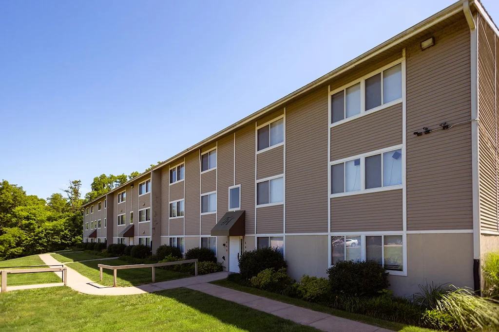 Apartment building with neutral siding, white doors, green awning