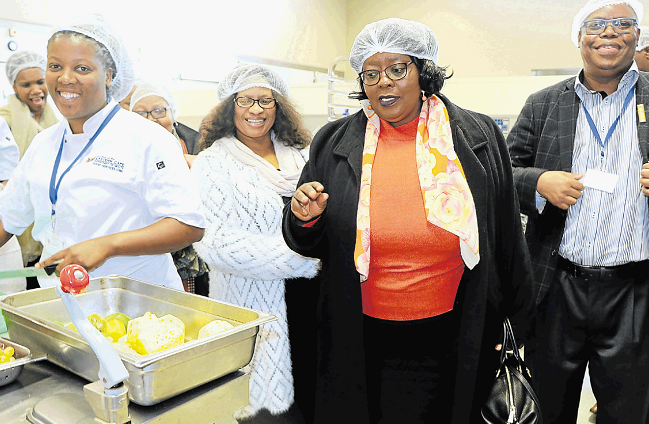 Ziyanda Mahlati prepares food for patients while national tourism department deputy minister Elizabeth Thabethe looks on at Cecilia Makiwane Hospital