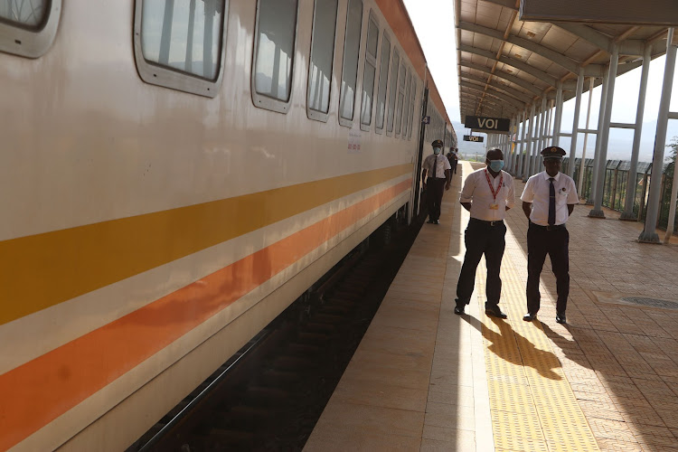 Kenya Railways attendants next to Madaraka Express Passenger Service train at Voi station, Taita Taveta county, on Wednesday