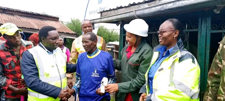 Kenya Power and Lighting Company regional manager in charge of Central Rift, Kipkemoi Kabias (Left) and Kipipiri MP, Wanjiku Muhia interact with a resident of Gatondo Location during the launch of a Sh12 million electricity project in area.