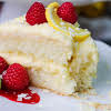 Thumbnail For A Slice Of Limoncello Creme Cake On A Plate With Lemon And Raspberries.