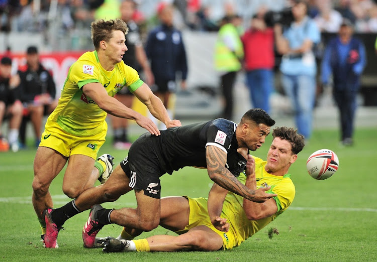 Matthew Hood of Australia (l) and teammate Simon Kennewell of Australia (r) combine to tackle Regan Ware of New Zealand during day 1 of the 2017 HSBC Cape Town Sevens at Cape Town Stadium on 9 December 2017.