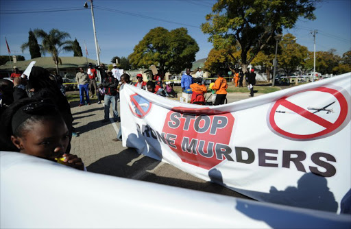 People hold a banner as they protest on June 28, 2013 outside the US embassy in Pretoria against the upcoming visit of US President Barak Obama in South Africa.