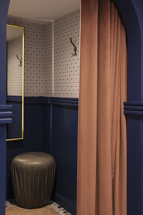 The fitting rooms with timber paneling, bespoke wallpaper and bespoke leather stools.