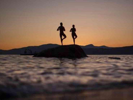 A couple stand on a rock facing the sunset along the shores of English Bay in Vancouver, British Columbia July 23, 2013. /REUTERS