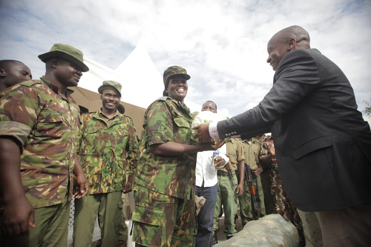 Interior CS Kithure Kindiki handing over a cabbageto one of the officers in Shakahola on May 25,2023.