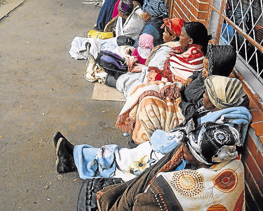 Social grant beneficiaries, mostly women, wait outside a Sassa office.