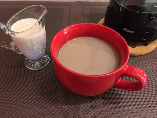 A cup of coffee with a small creamer next to it.