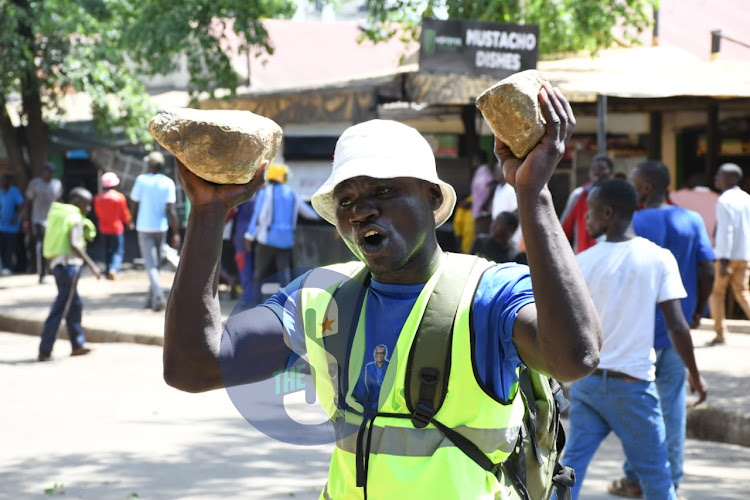 Kisumu resident carrying stones to demand for justice after three people were allegedly shot by police officers who were chasing a suspected matatu on May 9, 2023.