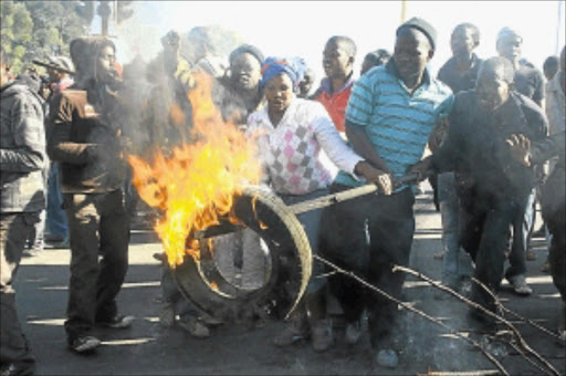 TENSE SITUATION: Zandspruit residents burning tyres and damaging streets signs as they protested for better service delivery yesterday. PHOTO: SIBUSISO MSIBI