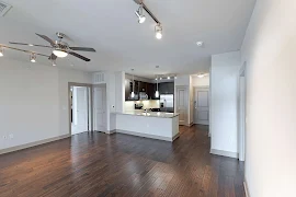 View from the living room looking towards the kitchen featuring dark cabinets, stainless steel appliances, and pendant lighting