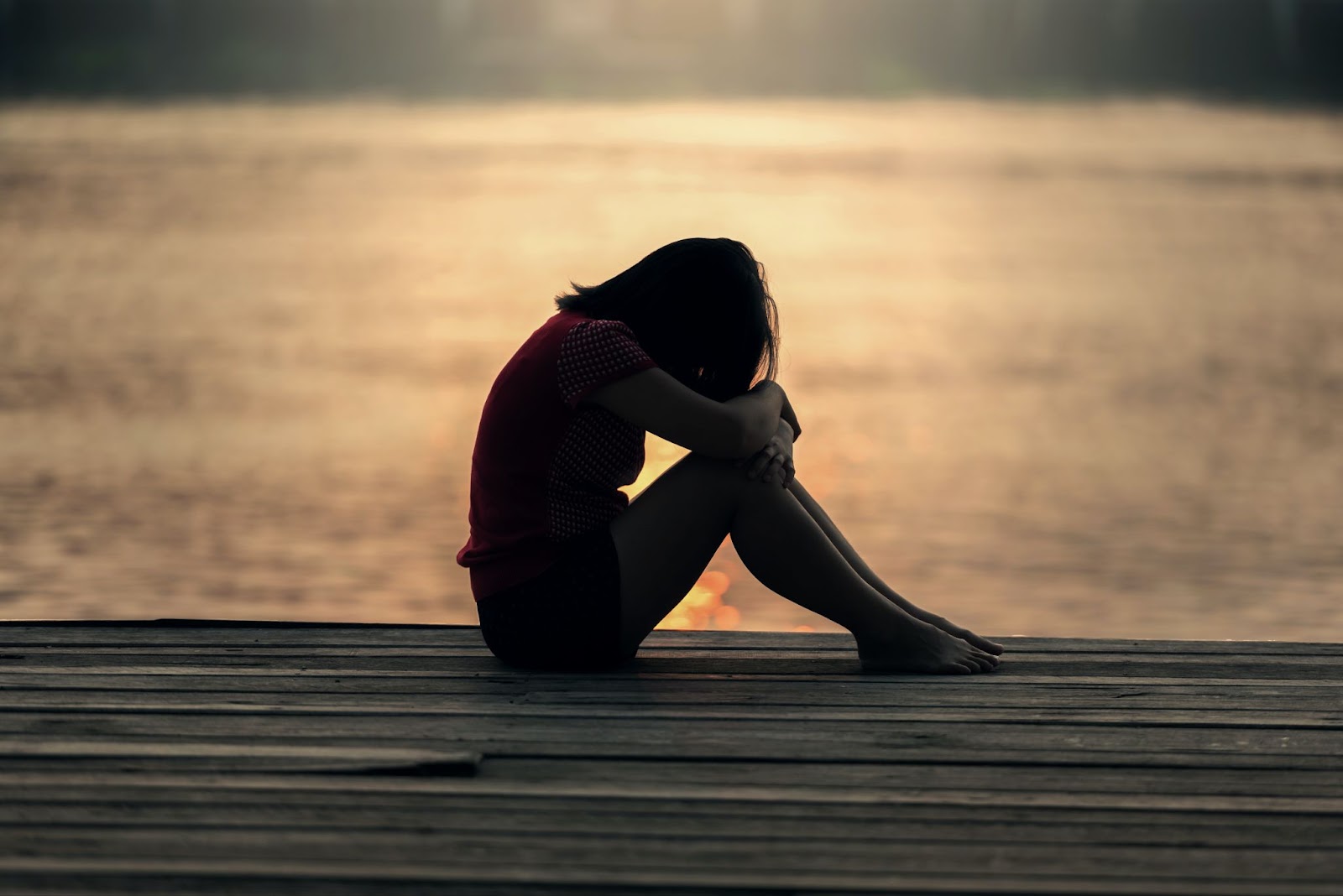 Woman sitting and resting her head on her knees after finding out she has chronic disease