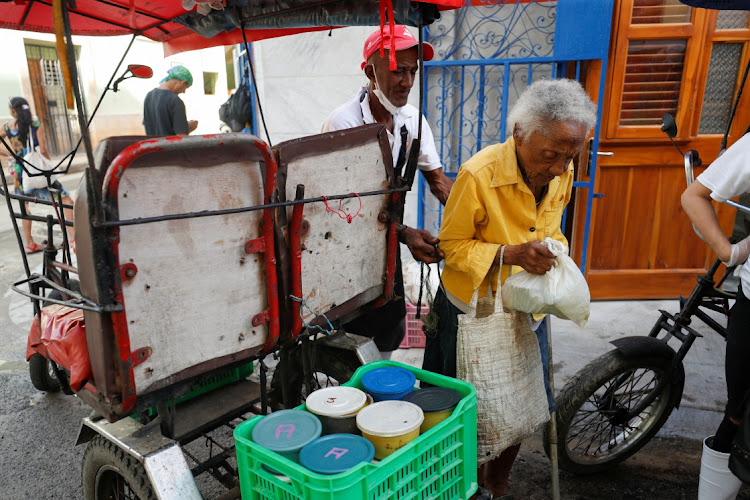 A woman carries a bag holding containers with food from a soup kitchen run by religious group Quisicuaba that is serving a growing number of Cubans struggling to make ends meet amid economic crisis, in Havana, Cuba January 15, 2024. REUTERS/Yander Zamora