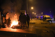 Search and rescue teams as well as affected families huddle around a fire in a street in the city of Adıyaman in Türkiye 