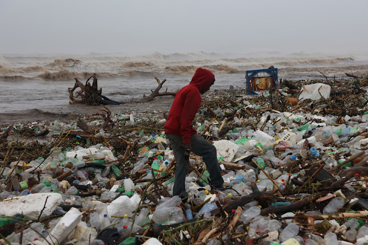 A resident surveys the destruction amid the debris on a Durban beach after areas of KwaZulu-Natal were hit by floods after heavy rains caused flooding.