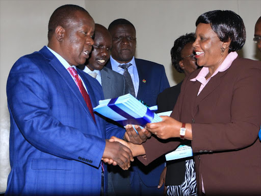 Education CS Fred Matiang'i receiving a task force report on school fires from Dr Gracie Mulei at the Kenya Institute of Curriculum Development on Friday. Looking on is Basic Education PS Belio Kipsang and other ministry officials. /EMMANUEL WANJALA