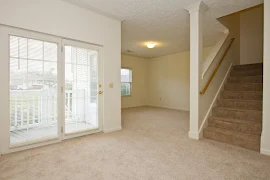 Carpeted dining area has a patio door, upstairs staircase on the right, and overlooks the living room ahead