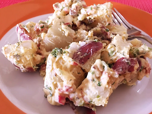 Potato salad on an orange plate with a fork