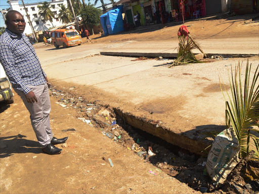 Shanzu MCA aspirant Martin Wekesa shows a section of the Bamburi road that has been destroyed by torrential rain in Mombasa county, May 24, 2017. /JOHN CHESOLI