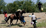 A US border patrol officer grabs the shirt of a migrant trying to return to the United States along the Rio Grande river, after having crossed from the United States into Mexico to buy food, as seen from Ciudad Acuna, in Ciudad Acuna, Mexico September 19, 2021 