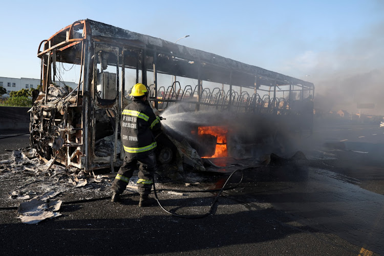 Firemen extinguish a burning bus on the first day of the taxi strike.