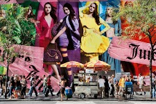 drukke straat met ijsverkoper waarachter een muur met foto's van vrouwen ieder in een andere kleur van de regenboog